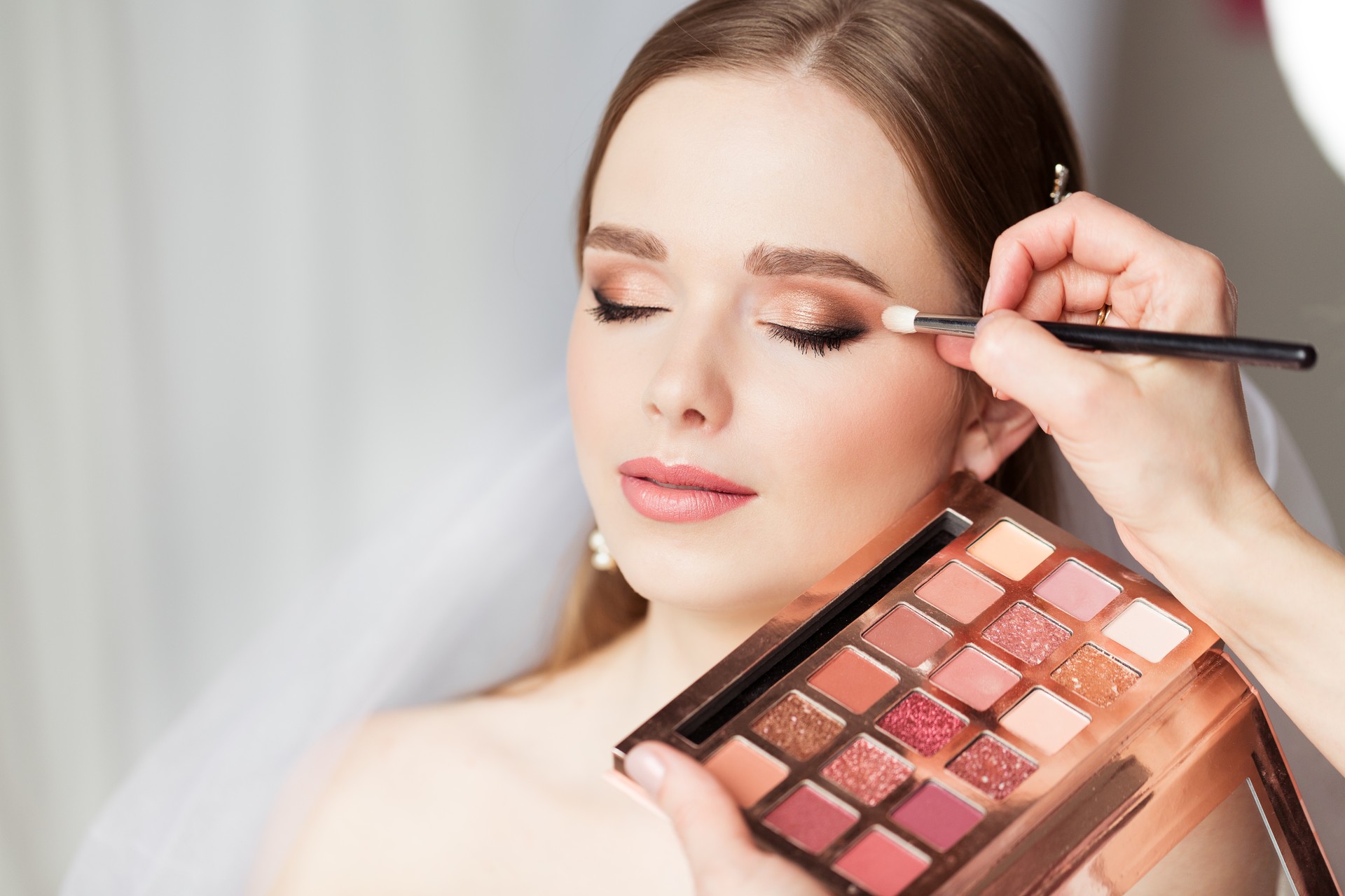 Wedding Make up Artist making Professional Bride Makeup. Bridal Eyeshadow Palette. Wedding Cosmetics Salon Face. Close up Beauty Bride Face Closed Eyes